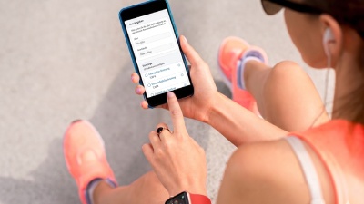 Sportliche Frau nutzt Bonusrechner auf Smartphone