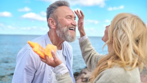 Frau cremt Mann mit Sonnencreme im Gesicht ein